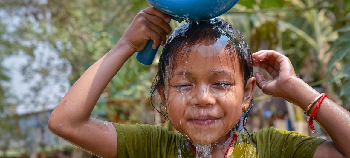 Seorang gadis muda mencuci wajahnya menggunakan air pipa yang baru dipasang di rumahnya di Kamboja.