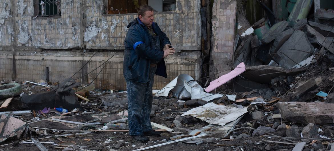 Житель Киева разбирает завалы разрушенного жилого дома.