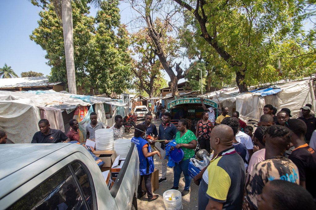 Trabajadores humanitarios distribuyen kits de higiene a un grupo de personas en un asentamiento improvisado en Puerto Príncipe, Haití.