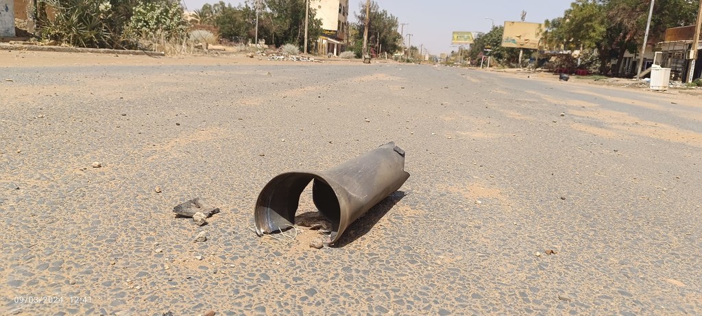 أنبوب معدني كبير، يُرجح أنه قذيفة غير منفجرة، يقع على طريق مهجور في منطقة النزاع في السودان.