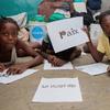 Ученица школы в Порт-о-Пренсе держит плакат с надписью "мир".