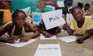 A schoolgirl in Port-au-Prince holds up a sign in French which reads 'peace'.