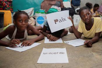 Une écolière de Port-au-Prince brandit une pancarte en français sur laquelle on peut lire « paix ».