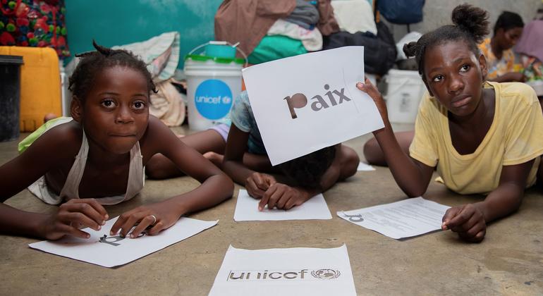 Une écolière de Port-au-Prince brandit une pancarte en français sur laquelle on peut lire « paix ».