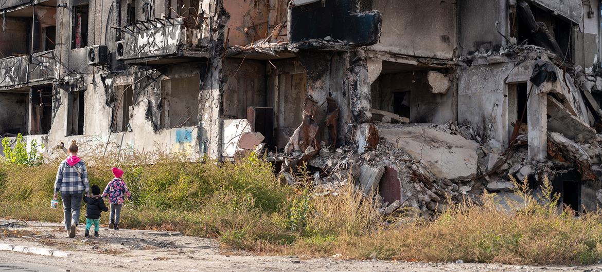 An adult and two children walk past a destroyed apartment block in Borodianka, Ukraine.