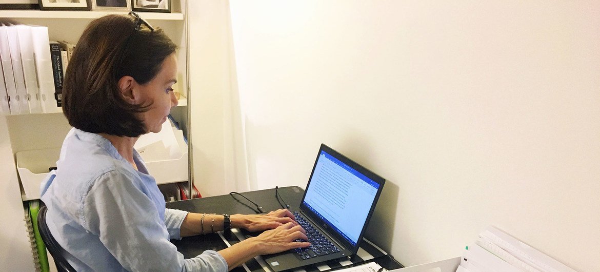 Uma mulher trabalha em uma mesa com um laptop em um escritório em casa.