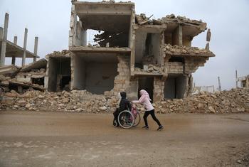 فتاة تدفع الكرسي المتحرك لشقيقتها أثناء عوتهما من المدرسة وسط الدمار في إدلب، شمال غرب سوريا.