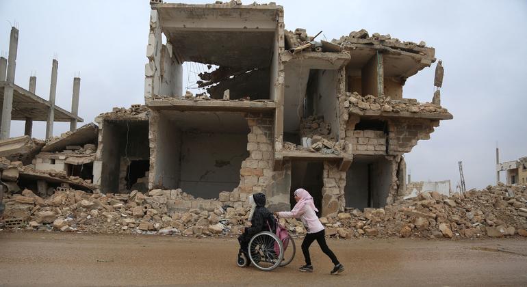 पश्चिमोत्तर सीरिया के इदलिब प्रान्त में युद्ध से तबाह हुए एक इलाक़े में एक लड़की अपनी बहन को व्हील चेयर पर लेकर जा रही है.