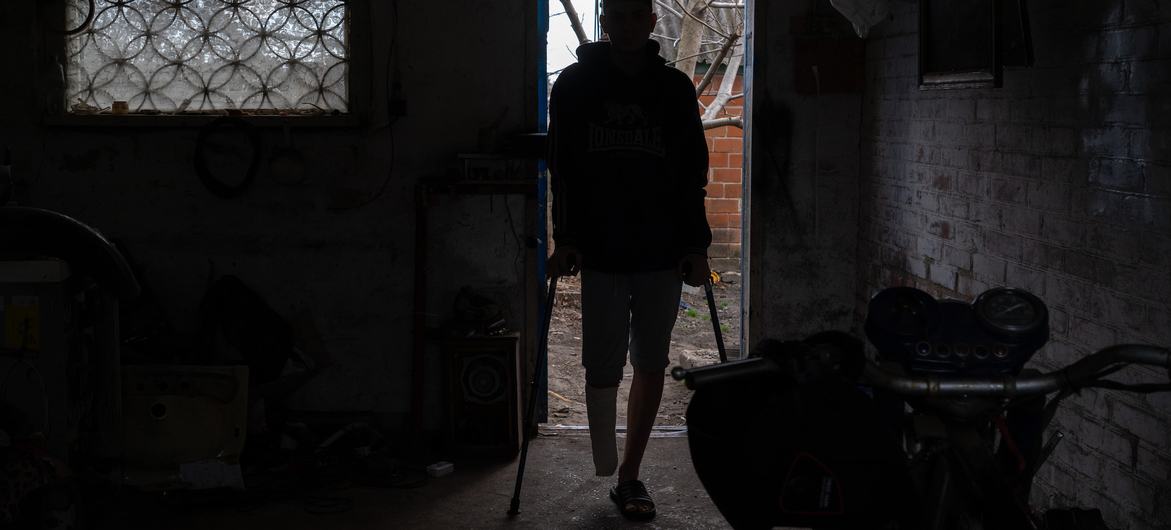 A 16-year-old boy, who lost his right leg in a landmine explosion and can no longer walk, stands on crutches at his house in Kharkiv, Ukraine.