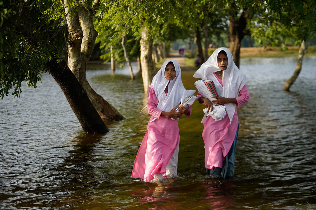 Unas niñas vadean las aguas de la inundación de camino a la escuela en Sunamganj, Bangladesh.
