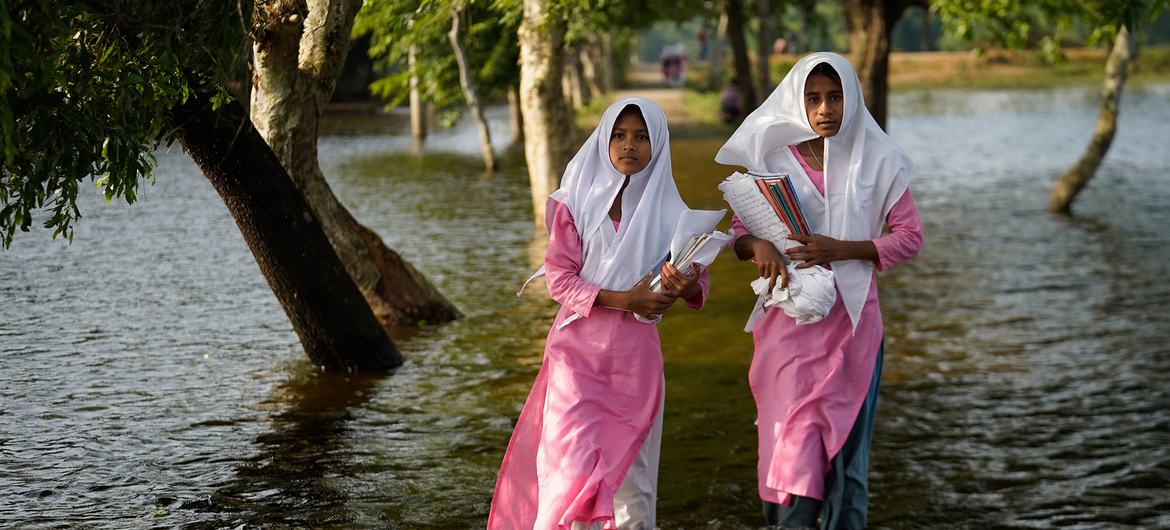 Unas niñas vadean las aguas de la inundación de camino a la escuela en Sunamganj, Bangladesh.