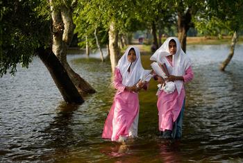 在孟加拉国的苏纳姆甘杰，女孩们在上学的路上趟过洪水。