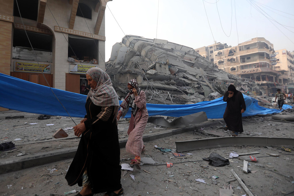 Wanawake katika kitongoji cha Nasr huko Gaza wakipita jengo lililoharibiwa na vifusi.