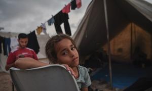 طفاة مع أسرتها في مكان إيواء يُقيم به المهجرون في قطاع غزة.