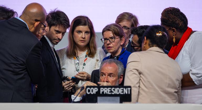 कॉप30 के अध्यक्ष आन्द्रे कोर्रया दो लागो (मध्य), समापन दौर में, अपनी टीम के साथ विचार-विमर्श करते हुए.