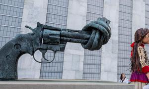 A view of Little Amal next to the Non-Violence or Knotted Gun sculpture by artist Carl Fredrik Reuterswärd on the UN Visitors Plaza.
