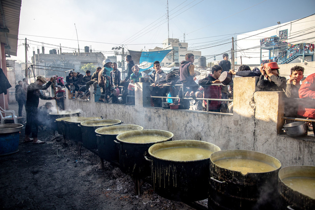 विस्थापित फ़लस्तीनी, रफ़ाह के अल-शबौरा शिविर में भोजन का इन्तज़ार करते हुए.