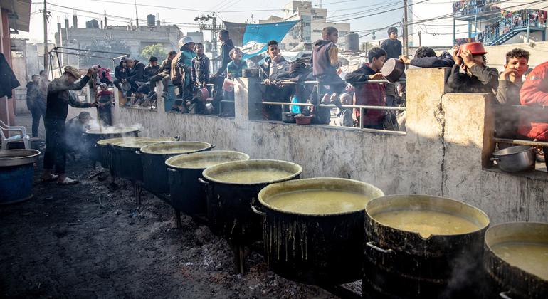Displaced Palestinians wait for food at Al-Shaboura camp, in Rafah.