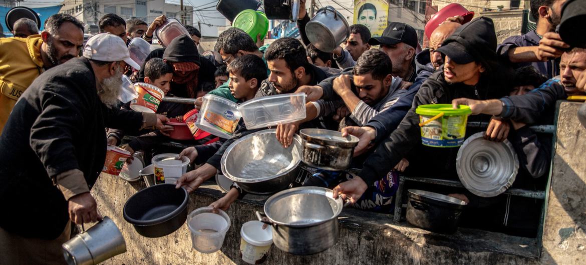 غزہ کے بحران میں بے گھر ہونے والے لوگ رفع کے ایک کیمپ میں خوراک ملنے کے منتظر ہیں۔