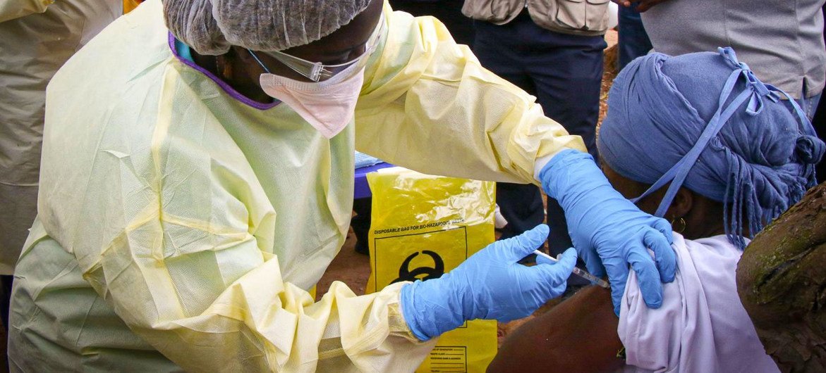 Un trabajador sanitario con equipo de protección administra una vacuna contra el Ébola a una persona en Guinea.