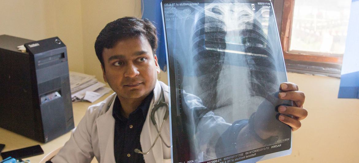 Na Índia, um médico verifica a radiografia de um paciente em busca de danos nos pulmões, o que pode indicar tuberculose