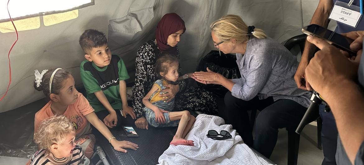 سيخريد كاخ تلتقي بطفلة تعاني من سوء التغذية وعائلتها في مستشفى الهيئة الطبية الدولية الميداني في غزة.