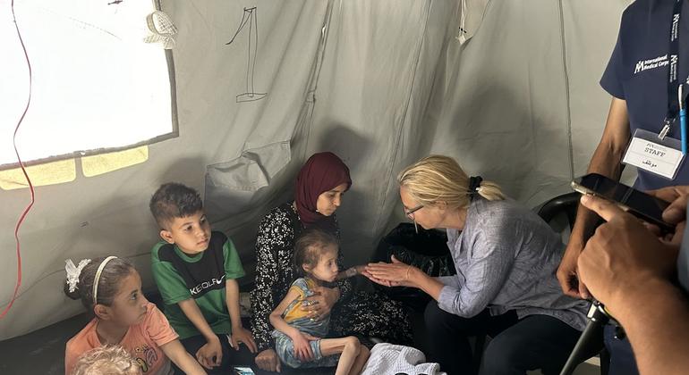 联合国驻加沙协调员西格丽德·卡格在国际医疗队中心会见一名营养不良的儿童及其家人。