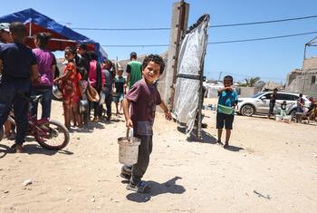 ایک فلسطینی بچہ غزہ کے علاقے خان یونس میں عالمی ادارہ خوراک کے تحت کام کرنے والے ’کچن‘ سے کھانا لے کر جا رہا ہے۔