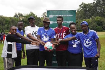 Peter Omondi (kati), Mkurugenzi Mkuu wa shirika la Global Youth Forum linalounganisha vijana Kenya, akiwa na vijana wachezaji wa mpira wa miguu.