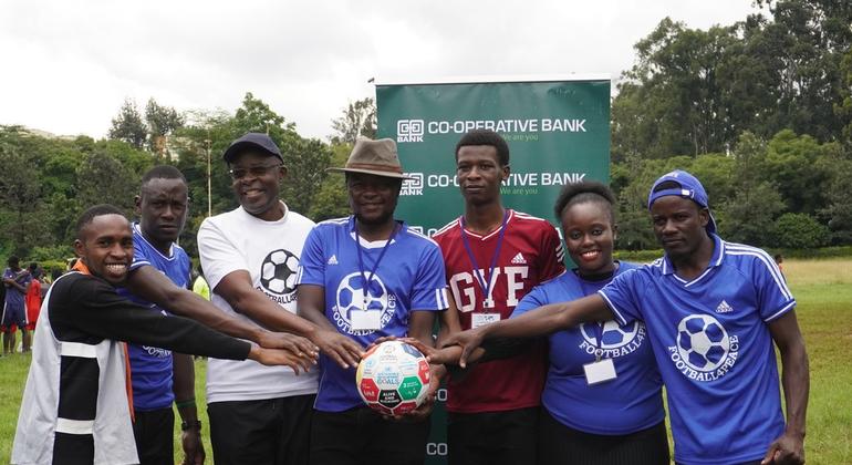 Peter Omondi (kati), Mkurugenzi Mkuu wa shirika la Global Youth Forum linalounganisha vijana Kenya, akiwa na vijana wachezaji wa mpira wa miguu.