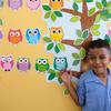 一名年轻的小学生面带灿烂的笑容站在一间多功能室里，房间里装饰着联合国难民署捐赠的各种心理教育材料。