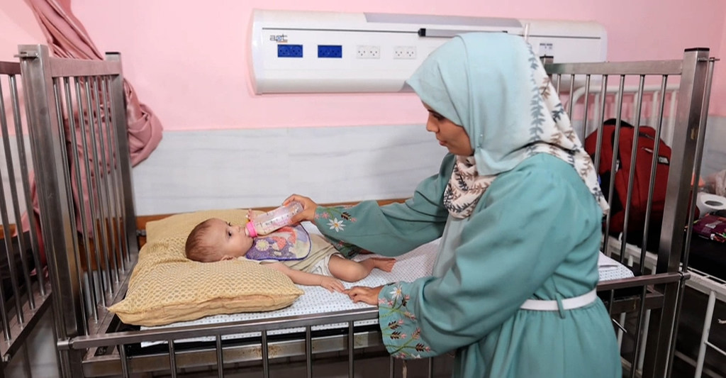 Una madre palestina en Gaza alimenta a su hijo pequeño, Ahmad, con un biberón en la sala de neonatología de un hospital.