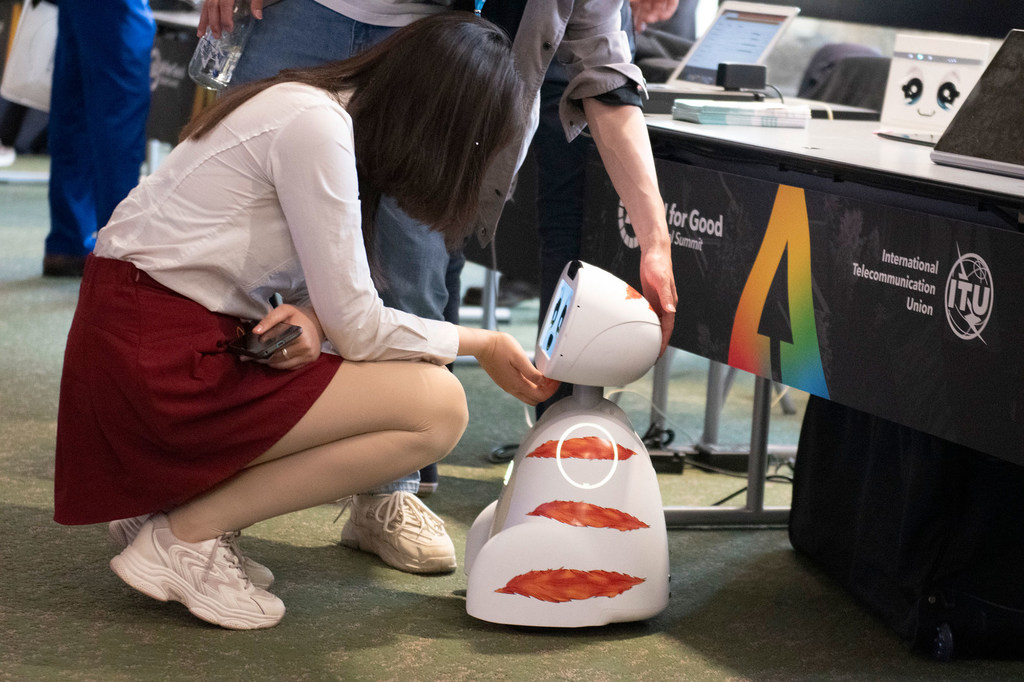 在日内瓦举行的2024年人工智能全球峰会上，一名女士向机器人打招呼。