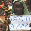 فتاة صغيرة تحمل لافتة كتب عليها شعار يقول Zo Kwe Zo، وهو الشعار الوطني لجمهورية أفريقيا الوسطى، ويعني أن جميع البشر متساوون.