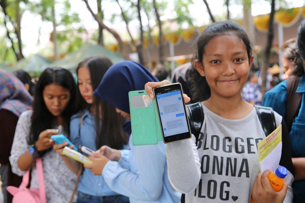 Adolescentes de Indonesia usando sus teléfonos móviles.