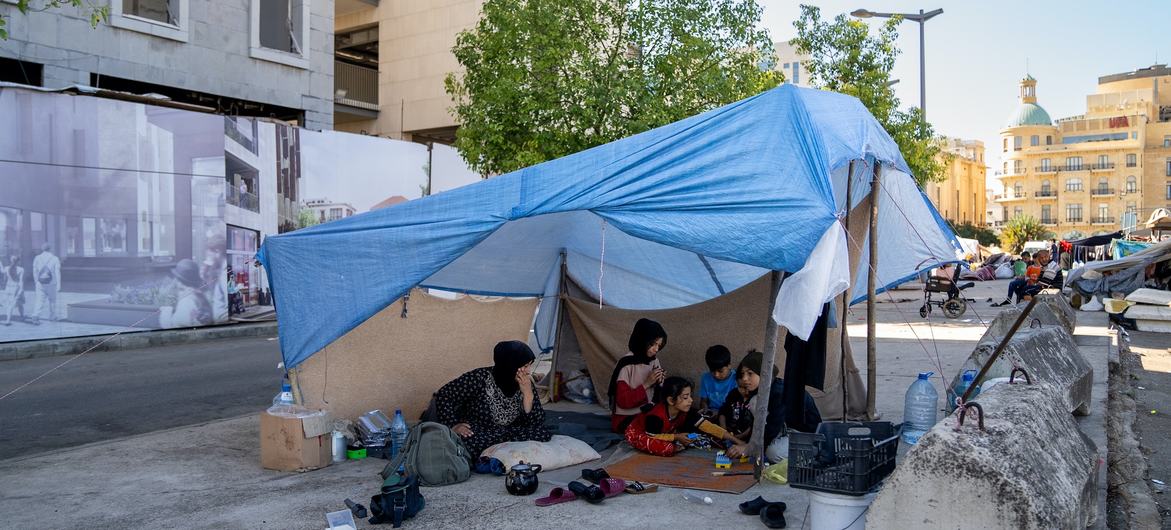 A mother with her children shelter under a tarp in Beirut after being driven from their home.