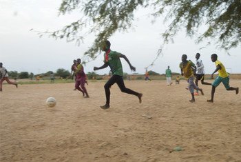 أطفال يلعبون كرة القدم في مساحة صديقة للأطفال تدعمها اليونيسف في بوركينا فاسو.
