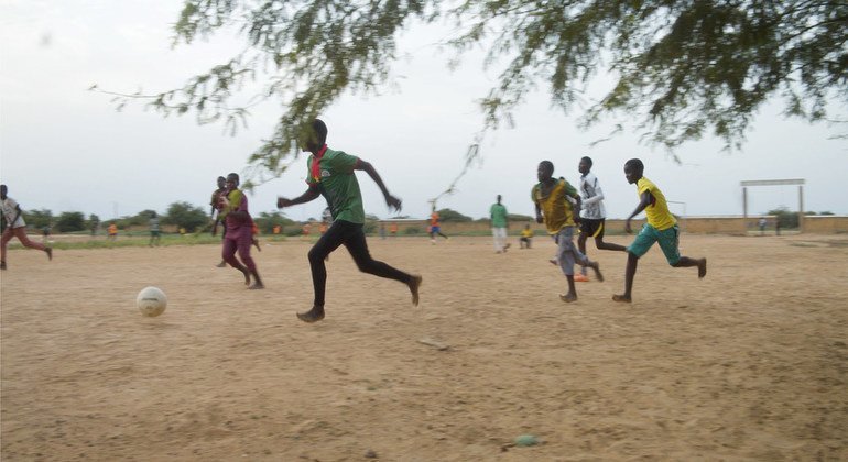 أطفال يلعبون كرة القدم في مساحة صديقة للأطفال تدعمها اليونيسف في بوركينا فاسو.
