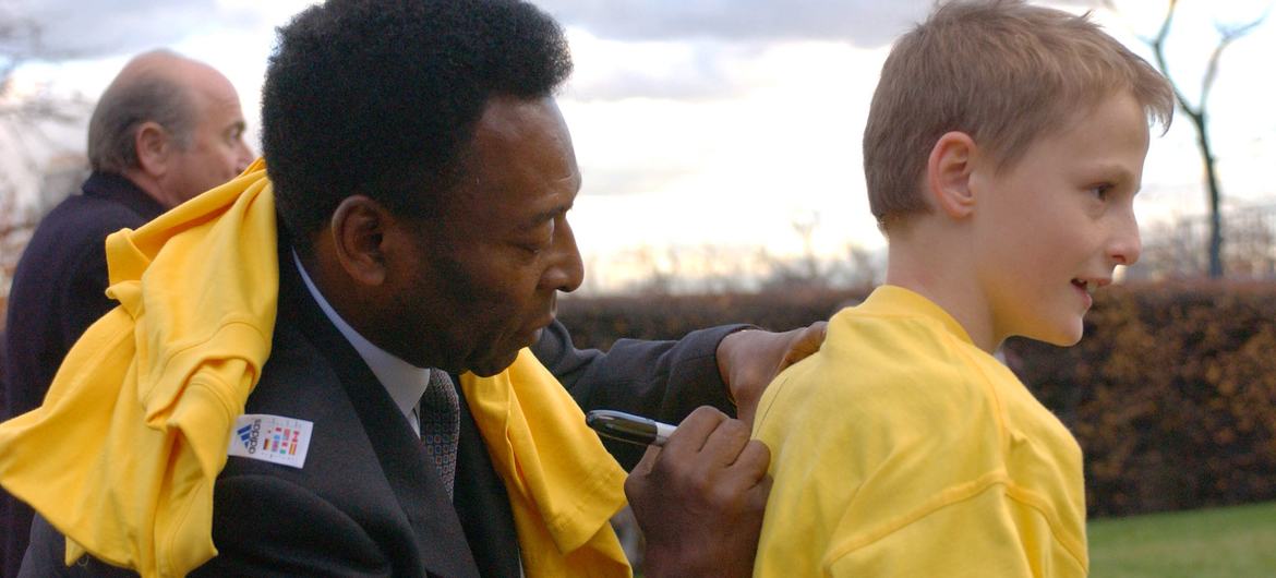 A lenda do futebol brasileiro Pelé assina seu nome nas costas de uma camiseta masculina, após o lançamento da Aliança FIFA-UNICEF para Crianças na sede da ONU. (novembro de 2001)