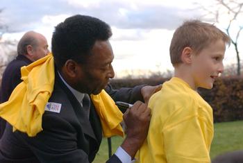 Brazilian football legend Pele signs his name on the back of a boy's t-shirt, following the launch of the FIFA-UNICEF Alliance for Children at UN headquarters. (November 2001)