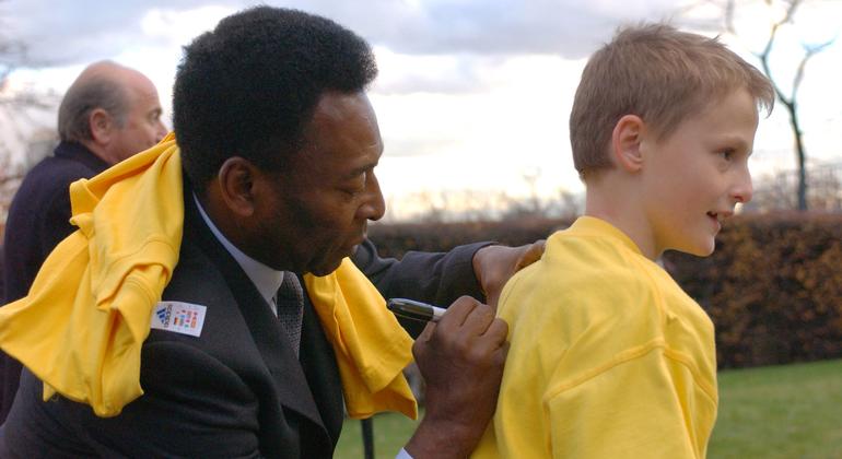 Brazilian football legend Pele signs his name on the back of a boy's t-shirt, following the launch of the FIFA-UNICEF Alliance for Children at UN headquarters. (November 2001)