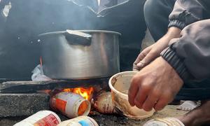 A family in Gaza uses plastic collected from the landfill to light a fire for cooking. (file)