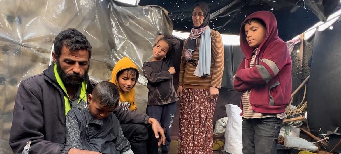 A família Mahmoud Al-Daqs preparando comida em sua tenda deteriorada