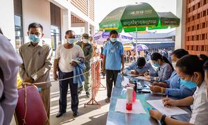 People wait in line to receive their COVID-19 booster shot at a hospital in Phnom Penh, Cambodia.