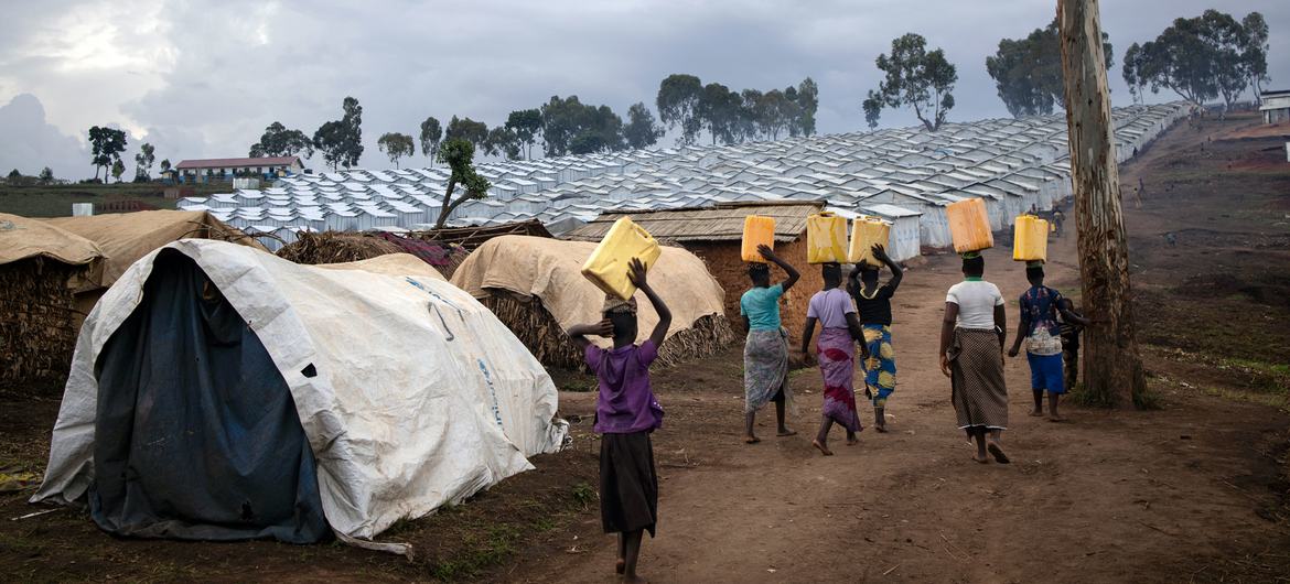 在伊图里省收容境内流离失所者的普莱恩萨沃营地，妇女在取水后返回临时住所。