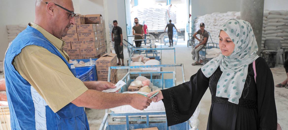 गाज़ा में UNRWA जबालिया वितरण केंद्र में एक फ़लिस्तीनी शरणार्थी महिला अपना भोजन सहायता पैकेज प्राप्त करते हुए.