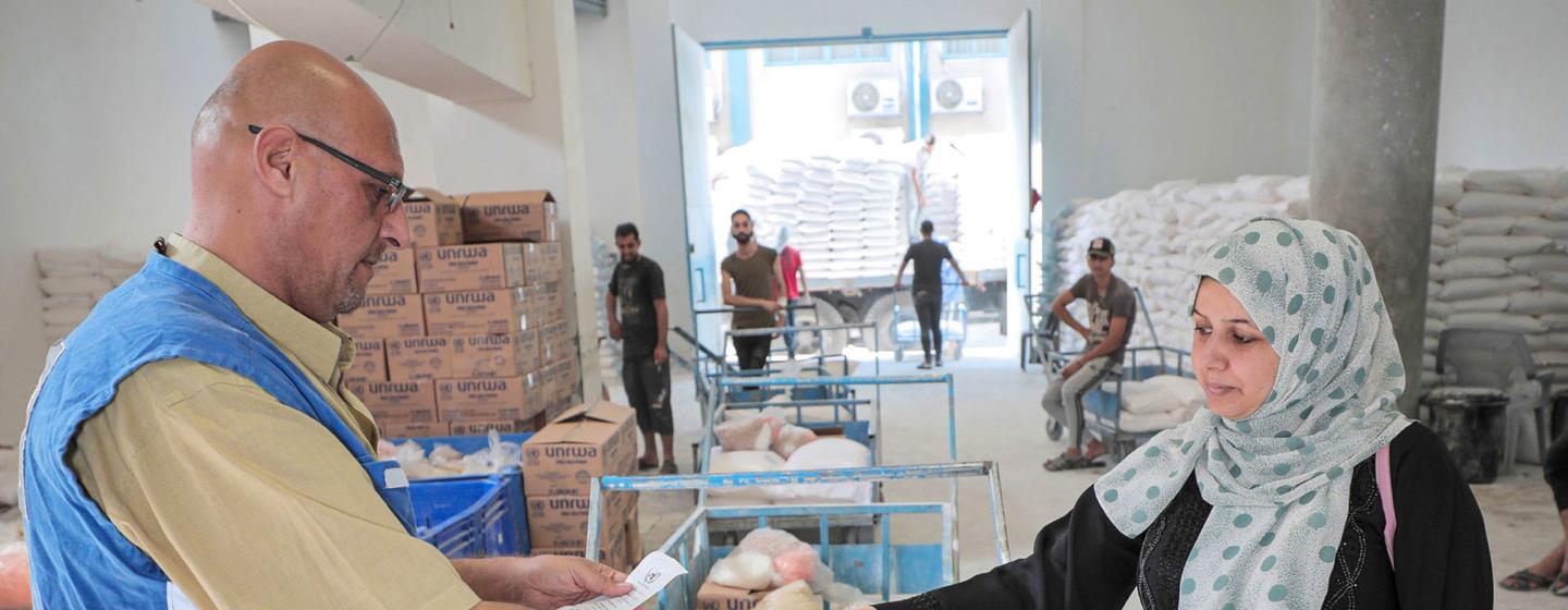 Une réfugiée palestinienne reçoit des colis d'aide alimentaire au centre de distribution de l'UNRWA à Jabalia, à Gaza.