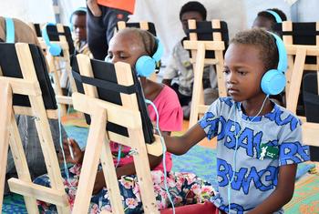 Children displaced by conflict engage in digital learning at a safe learning space in Port Sudan.