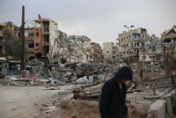 A man walks through a landscape of destroyed buildings and rubble in Harasta, East Ghouta, Syria.