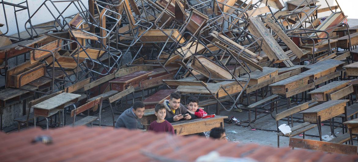 一群孩子坐在一所学校的课桌前，这所学校在2月份的地震后被用作避难所。